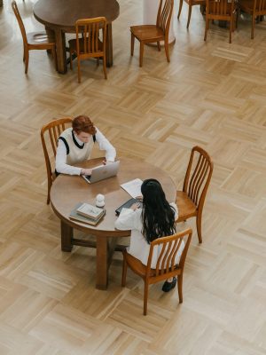 Two students collaborating on schoolwork at a library table.