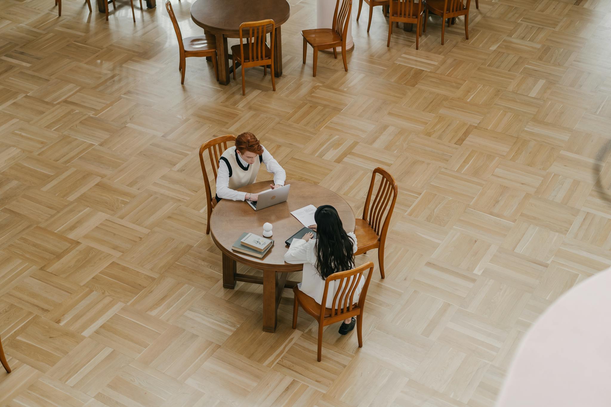 Two students collaborating on schoolwork at a library table.